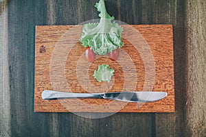 Vegetables made angry face on a cutting board on a light wooden table Tomatoes, lettuce,knife.