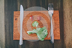 Vegetables made angry face on a cutting board on a light wooden table Tomatoes, lettuce,knife.vegetables make angry face on a cutt