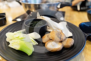 Vegetables and mushrooms on a black plate for hot pot