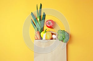 Vegetables in paper bag on yellow background