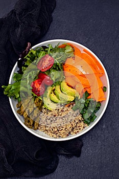 Vegetables with quinoa in white bowl on dark background