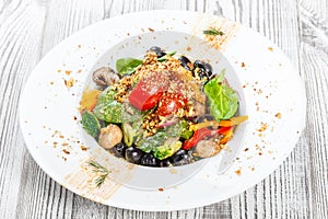 Vegetables salad with spinach, mushrooms, tomatoes, onions, cucumbers, broccoli, olives and nuts on plate