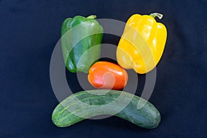 The vegetables on the scowl are white cabbage. Yellow bell peppers, red tomatoes and cucumbers on a black background