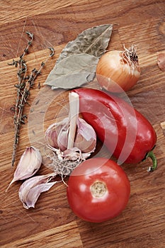 Vegetables and seasonings are on the wooden table. View from above