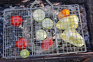 Vegetables slices between grill grates during grilling on brazier, outdoors