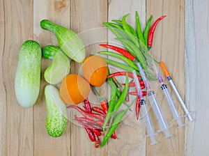 Vegetables and syringe on wooden table