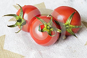 Vegetables on the table, three tomatoes on the white table cloth