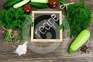 Vegetables, tomato, cucumber, courgette, dill and parsley on wooden background. Recipe table cuisine