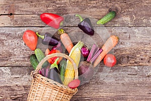 Vegetables in a wicker basket on a wooden background. Fresh crops, farm products, a vegetable garden at home. Copy space