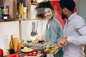 Vegetarian african-american couple cooking salad in kitchen