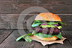 Vegetarian beet burger with avocado and spinach against dark wood