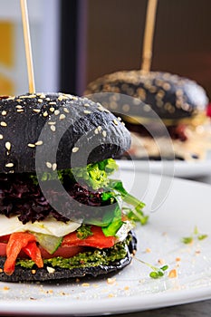 Vegetarian black burger with mozzarella, tomato and pepper. No meat food. Vegetarian fast food