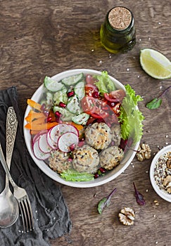 Vegetarian buddha bowl - quinoa meatballs and vegetable salad on wooden background, top view. Healthy, vegetarian food