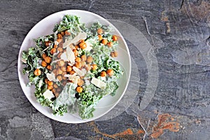 Vegetarian plant based Caesar salad with chickpeas, kale and a yogurt dressing. Top down view on a slate background. photo