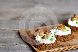 Vegetarian canape with soft cheese and mushrooms on a board on a wooden table