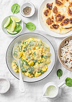 Vegetarian chickpea, spinach, potato curry, wild rice and naan flatbread on white background, top view. Indian healthy food