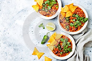 Vegetarian chili con carne with lentils, beans, nachos, lime, jalapeno. Mexican traditional dish.