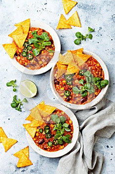 Vegetarian chili con carne with lentils, beans, nachos, lime, jalapeno. Mexican traditional dish.
