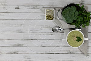 Vegetarian cream of broccoli, potato, onion, garlic, sesame and olive oil, and coconut milk soup. served in a white ceramic plate