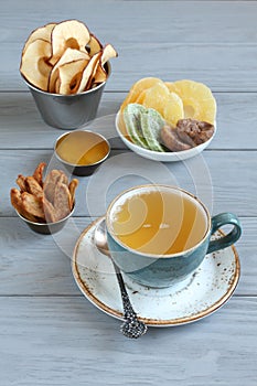 Vegetarian dessert: pieces of candied pineapple, kiwi and mango, dried figs, apple and pear chips in small bowls, honey