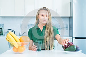 Vegetarian diet trend. Smiling young woman drinking green smoothie in kitchen. Green juice. Vegan meal diet at home