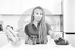 Vegetarian diet trend. Smiling young woman drinking green smoothie in kitchen. Green juice. Vegan meal diet at home