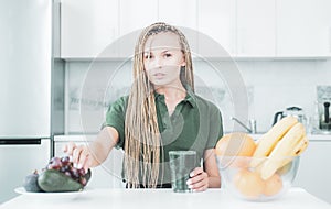 Vegetarian diet trend. Smiling young woman drinking green smoothie in kitchen. Green juice. Vegan meal diet at home