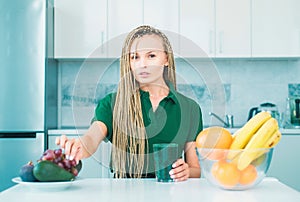 Vegetarian diet trend. Smiling young woman drinking green smoothie in kitchen. Green juice. Vegan meal diet at home