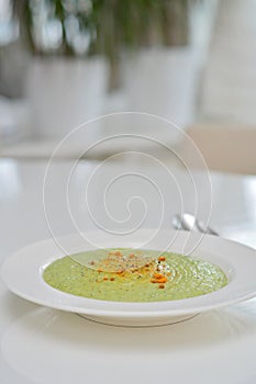 Vegetarian diet and vegan food, green healthy broccoli soup on a plate on a clean kitchen table. Tasty and nutritious meal, lunch