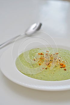 Vegetarian diet and vegan food, green healthy broccoli soup on a plate on a clean kitchen table. Tasty and nutritious meal, lunch