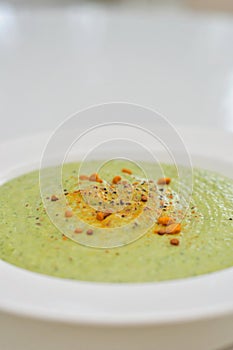 Vegetarian diet and vegan food, green healthy broccoli soup on a plate on a clean kitchen table. Tasty and nutritious meal, lunch