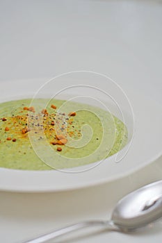 Vegetarian diet and vegan food, green healthy broccoli soup on a plate on a clean kitchen table. Tasty and nutritious meal, lunch