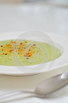 Vegetarian diet and vegan food, green healthy broccoli soup on a plate on a clean kitchen table. Tasty and nutritious meal, lunch