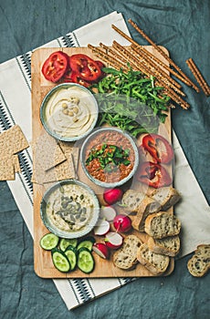 Vegetarian dips hummus, babaganush, muhammara on wooden board