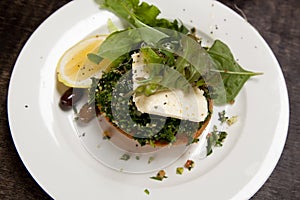 Vegetarian dish with tabbouleh, feta cheese, rocket, olives and lemon setting on top of a pumpkin pie