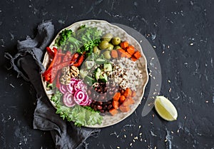 Vegetarian food bowl. Quinoa, beans, sweet potatoes, broccoli, peppers, olives, cucumber, nuts - healthy lunch. On the dark table