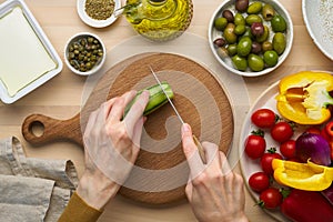 Vegetarian food. Chopping cucumber, cutting vegetables for greek salad horiatiki.