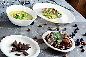 Vegetarian food, green cream soup, sala with asparagus and cherry tometoes, banana and vegan chocolate ice cream