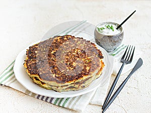 Vegetarian food - zucchini fritters on white background with sour cream sauce in a ceramic gravy boat. Close up, copy