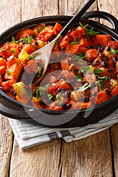 Vegetarian fried sweet potato black bean chili with tomatoes close-up in a pan. vertical