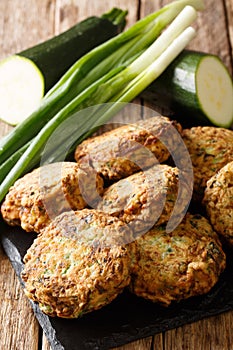 Vegetarian greek zucchini balls kolokithokeftedes close-up on a slate board. vertical