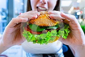 Vegetarian hamburger healthy vegan burger. Cute cheerful girl eating veggie sandwich with salad, avocado, vegetable