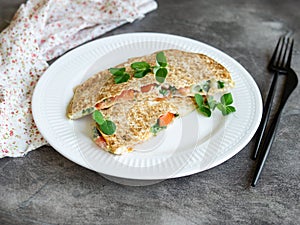 Vegetarian healthy breakfast of melted thin pita bread, cheese, tomato and herbs on a white plate and gray background