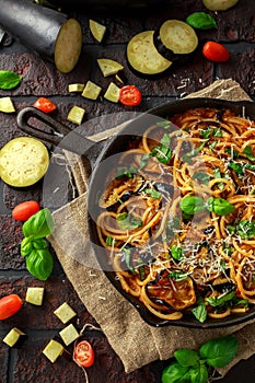 Vegetarian Italian Pasta Spaghetti alla Norma with eggplant, tomatoes, basil and parmesan cheese in rustic skillet pan.