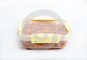 Vegetarian jollof rice with soy meat in a transparent lunch box on a white background