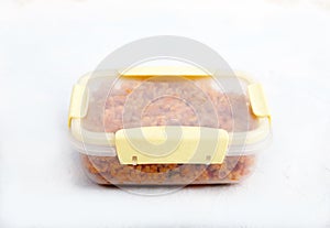 Vegetarian jollof rice with soy meat in a transparent lunch box on a white background