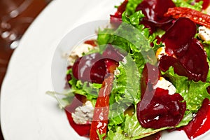 Vegetarian kitchen & healthy food concept. Fresh vegetable salad of sun-fried tomatoes, lettuce, beet and caprine cheese on white