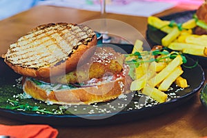 Vegetarian lentil burger in wholewheat bun with lettuce, tomato and cucumber accompanied by French fries Selective Focus