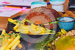 Vegetarian lentil burger in wholewheat bun with lettuce, tomato and cucumber accompanied by French fries Selective Focus