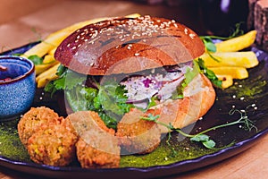 Vegetarian lentil burger in wholewheat bun with lettuce, tomato and cucumber accompanied by French fries Selective Focus